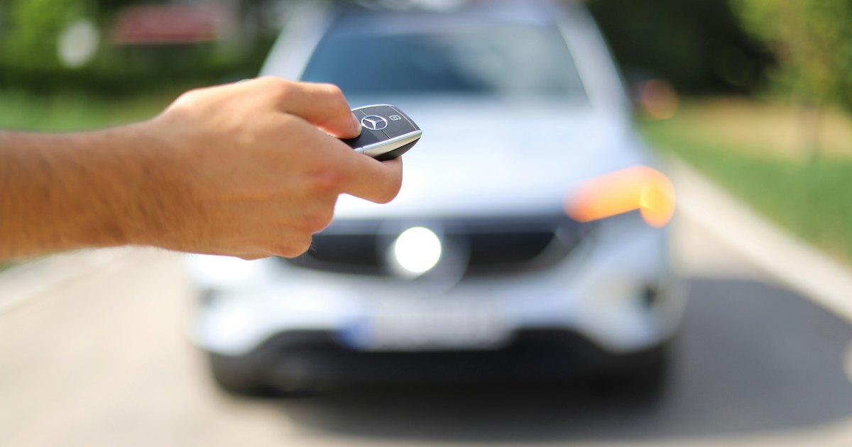 Ruka s ključem automobila ispred automobila