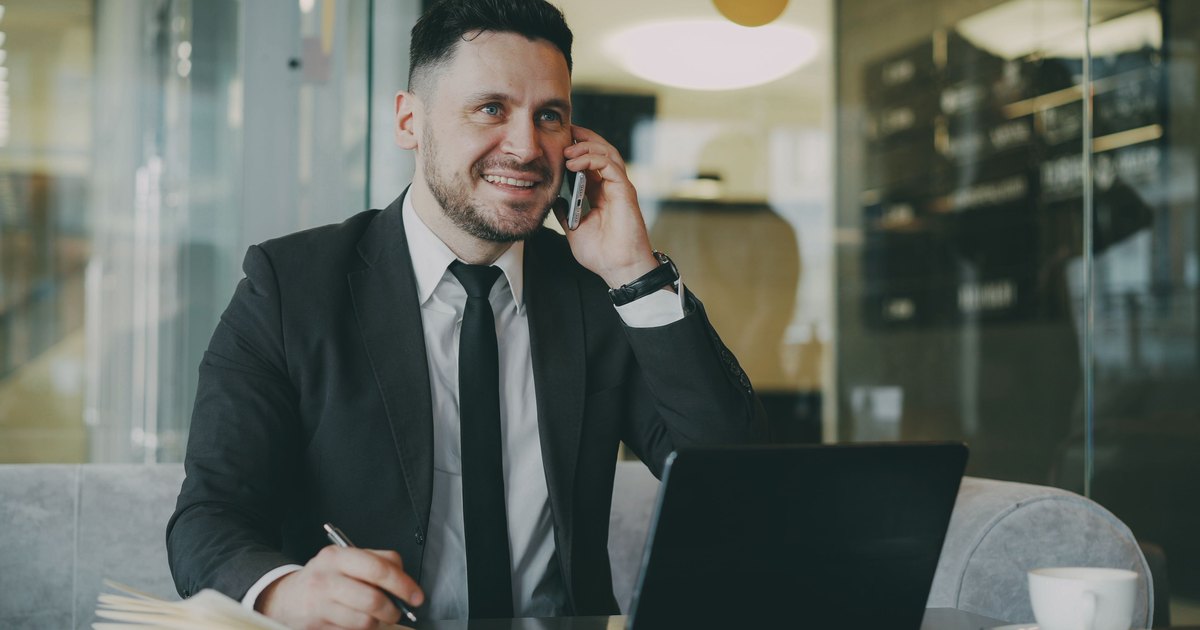 Poslovni čovjek telefonira uz dokumente i prijenosno računalo
