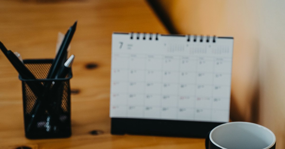 Stolni kalendar i olovke na radnom stolu, planiranje godišnjeg odmora